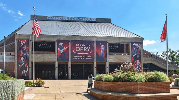 A building with signs that say "Grand Ole Opry" and an area with plants in front