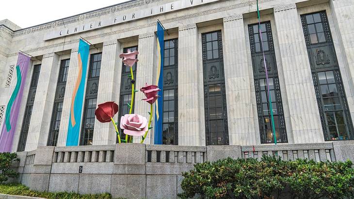 A stone museum building with colorful banners and rose sculptures in front of it A stone museum building with colorful banners and rose sculptures in front of it
