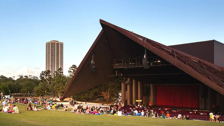 An open-air theater with a pointed roof and grass in front of it
