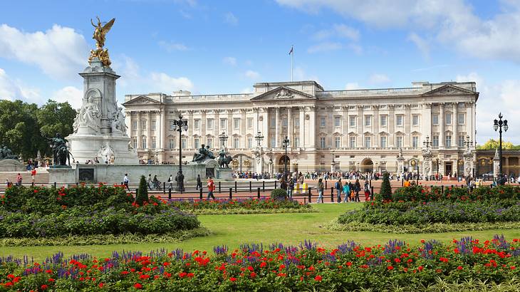 A palace with neoclassical architecture and a statue & garden in front