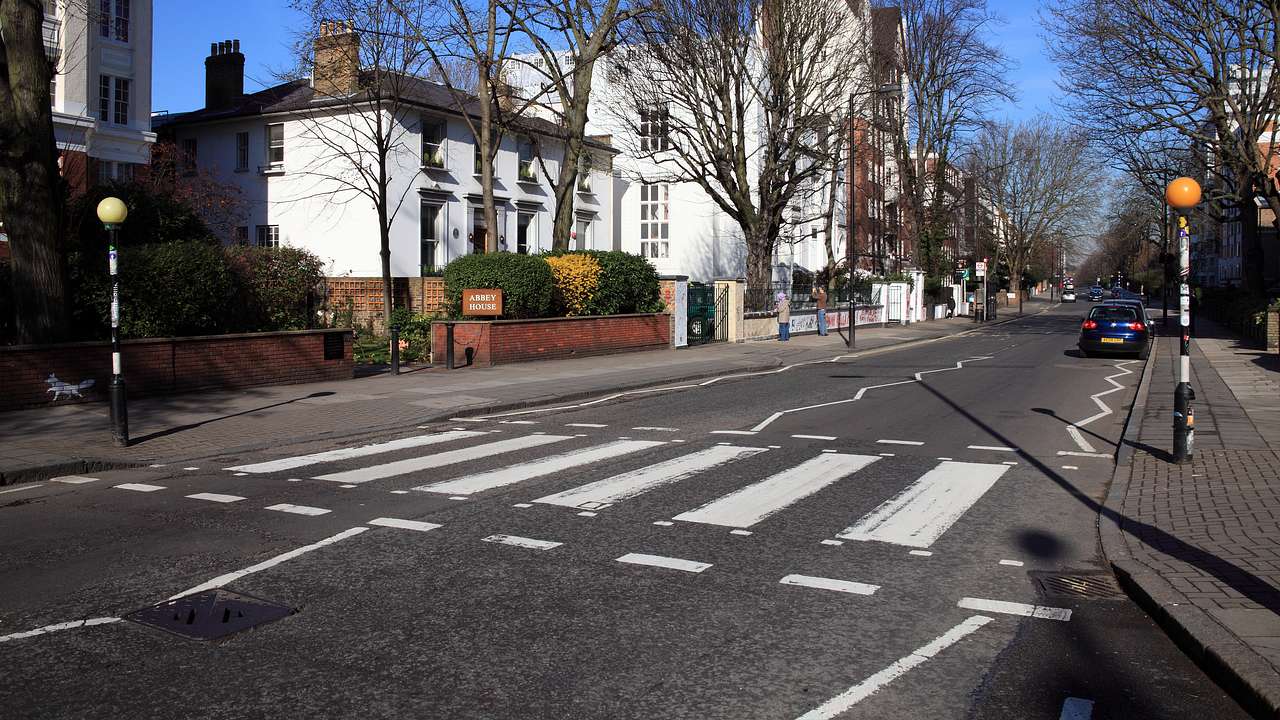 A zebra crossing on the road against some white houses under a blue sky