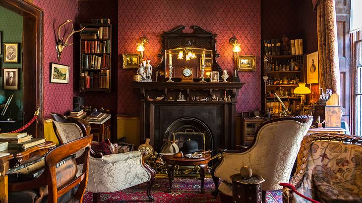 A red room with two white fabric chairs and a table against a fireplace