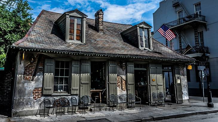 An old tavern-style building with an American flag and chairs outside