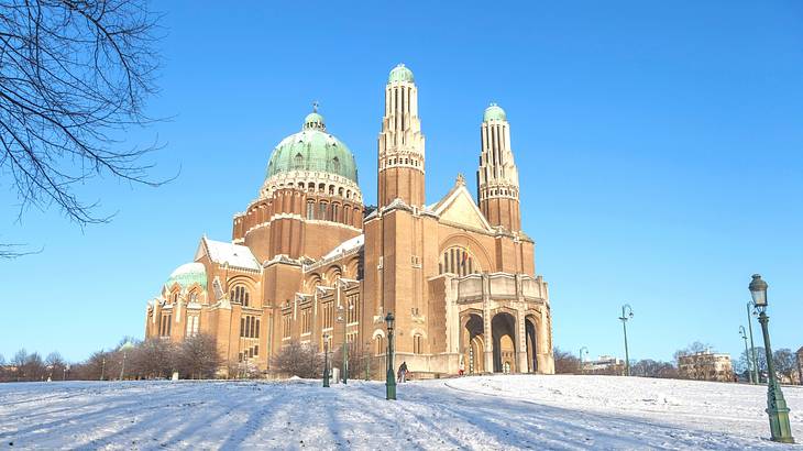 The outside of a basilica against a blue sky with snow on the ground