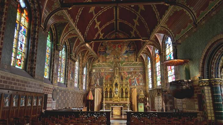 Church interior with stained glass windows and a large wall painting behind the altar