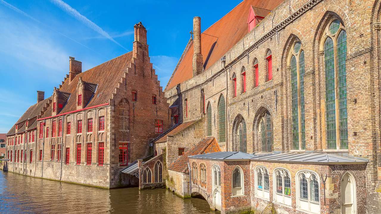 Historic brick buildings on the right side of a canal on a sunny day