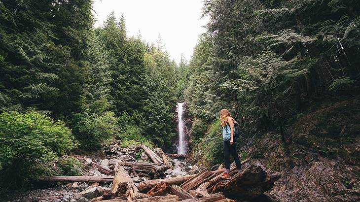Lady standing on a rock in front of a waterfall during a hike, Norvan Falls, BC