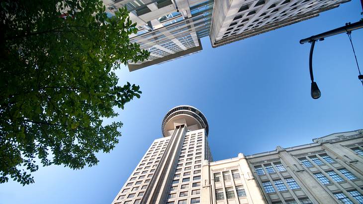 Looking up at a lookout tower and blue sky above with other buildings around