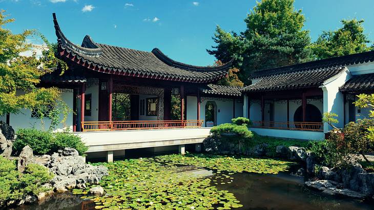 A classical Chinese garden with a pond in front and pagoda-like buildings at the back