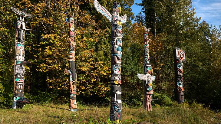 Tall Indigenous totem poles amongst greenery Tall Indigenous totem poles amongst greenery