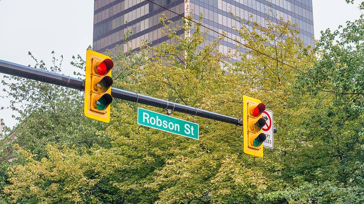 A photo of the Robson Street sign with traffic lights against green trees