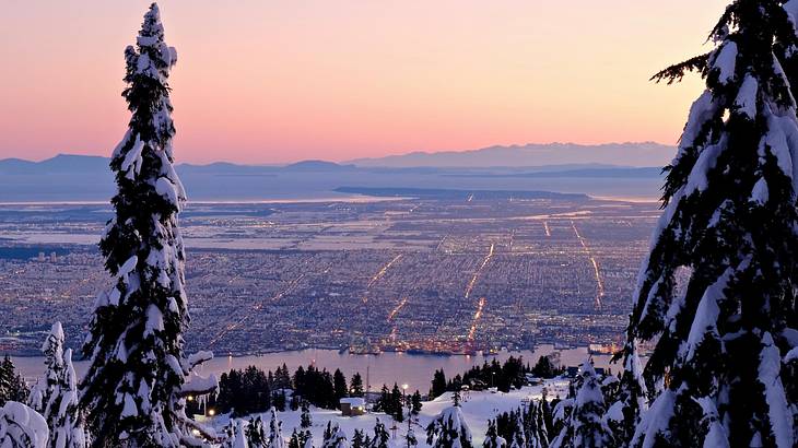 View of a city below at sunset from a mountain top in winter, Vancouver, BC, Canada