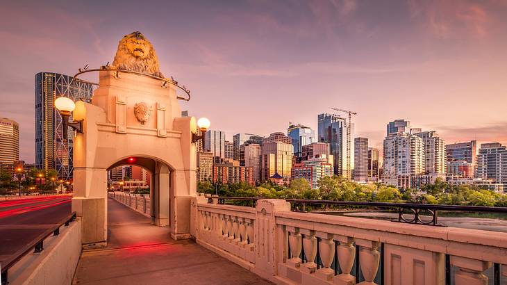 A decorated archway on a bridge in Calgary with buildings in the background, Alberta