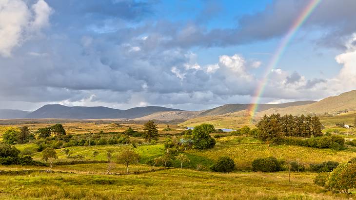 Rainbow over a green field with a mountain range in the background