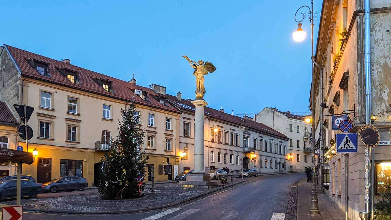 A street with an angel statue in the middle and buildings on the sides