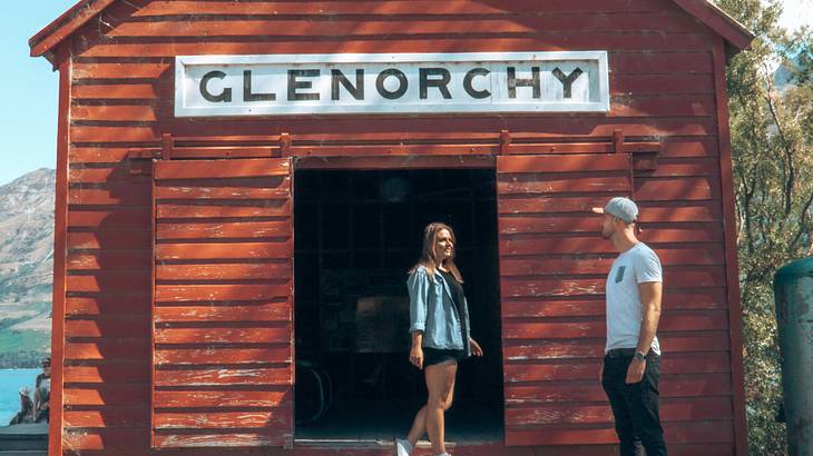 Man and woman looking at each other in front of the Glenorchy boatshed, New Zealand