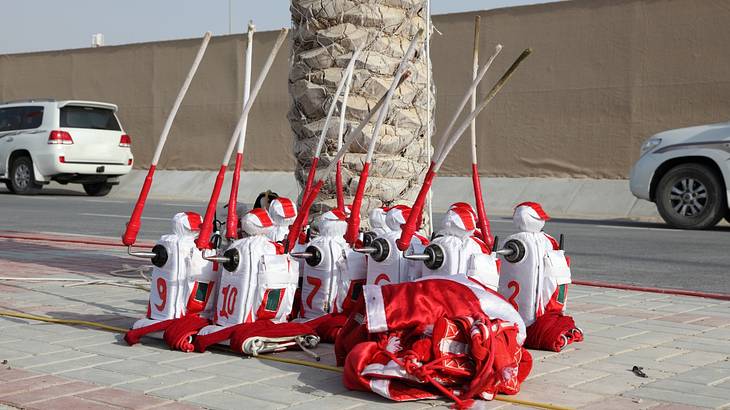 Jockey robots dressed in red and white on a sidewalk holding long sticks