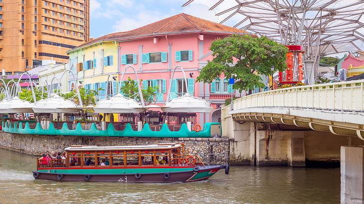 Colourful buildings, a walkway over water and a boat in Clark Quay, Singapore