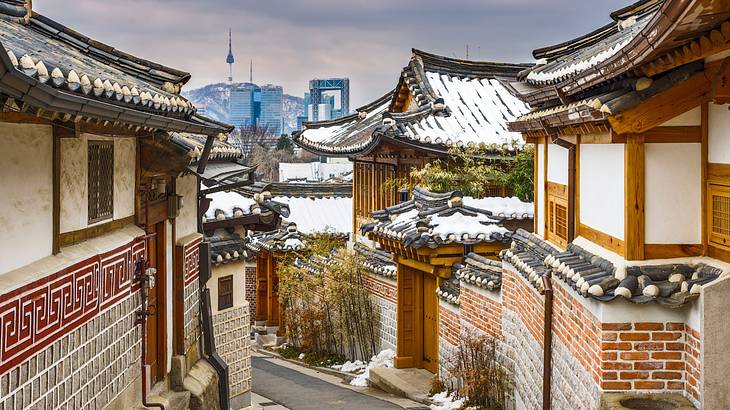 Traditional Korean houses with snow on the roofs and a pathway in the middle