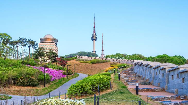 A park with an observation tower, greenery, and colourful flowers