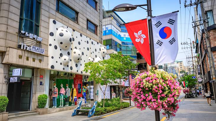 A street with a shop with polka dots on it next to a Korean flag and flowers