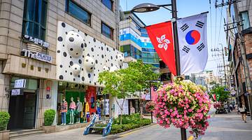A street with a shop with polka dots on it next to a Korean flag and flowers