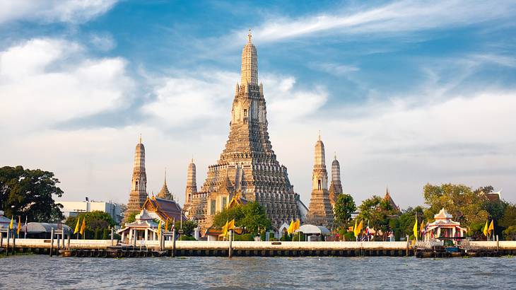 A temple structure with five towers next to water under a partly cloudy sky