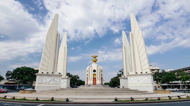 A monument with four white stone towers under a blue sky with clouds