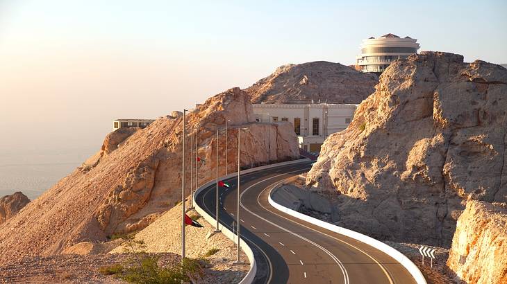 A road going up a mountain with a dry, arid landscape with a building at the top A road going up a mountain with a dry, arid landscape with a building at the top