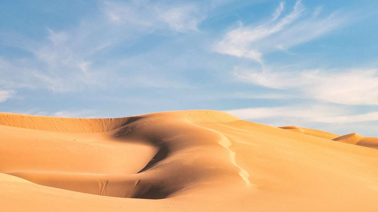 Sand dunes under a blue sky with light clouds