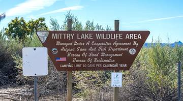 A sign that says "Mittry Lake Wildlife Area" surrounded by green plants