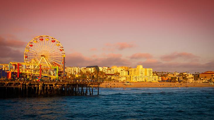 A theme park on a pier with a beach and buildings in the background