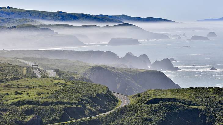 A winding road through foggy mountains overlooking the ocean