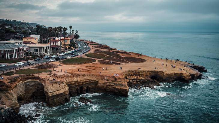 Aerial view of a rocky cliff with beach mansions overlooking the ocean