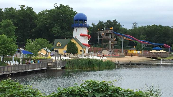 A lake surrounded by a park with rides, some houses, and green trees A lake surrounded by a park with rides, some houses, and green trees