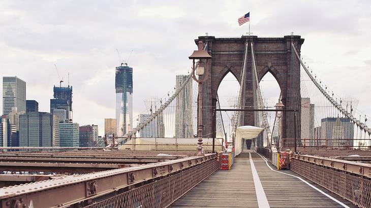 View on a large suspension bridge with a city skyline in the distance View on a large suspension bridge with a city skyline in the distance