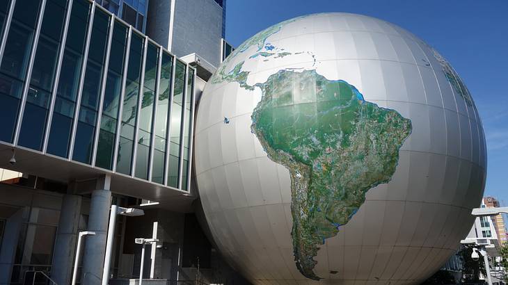 A large globe structure next to a building with glass windows
