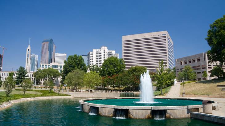 A water feature in a park with a city skyline behind it