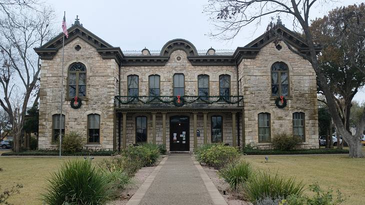 Limestone mansion at the end of a path walk surrounded by green grass