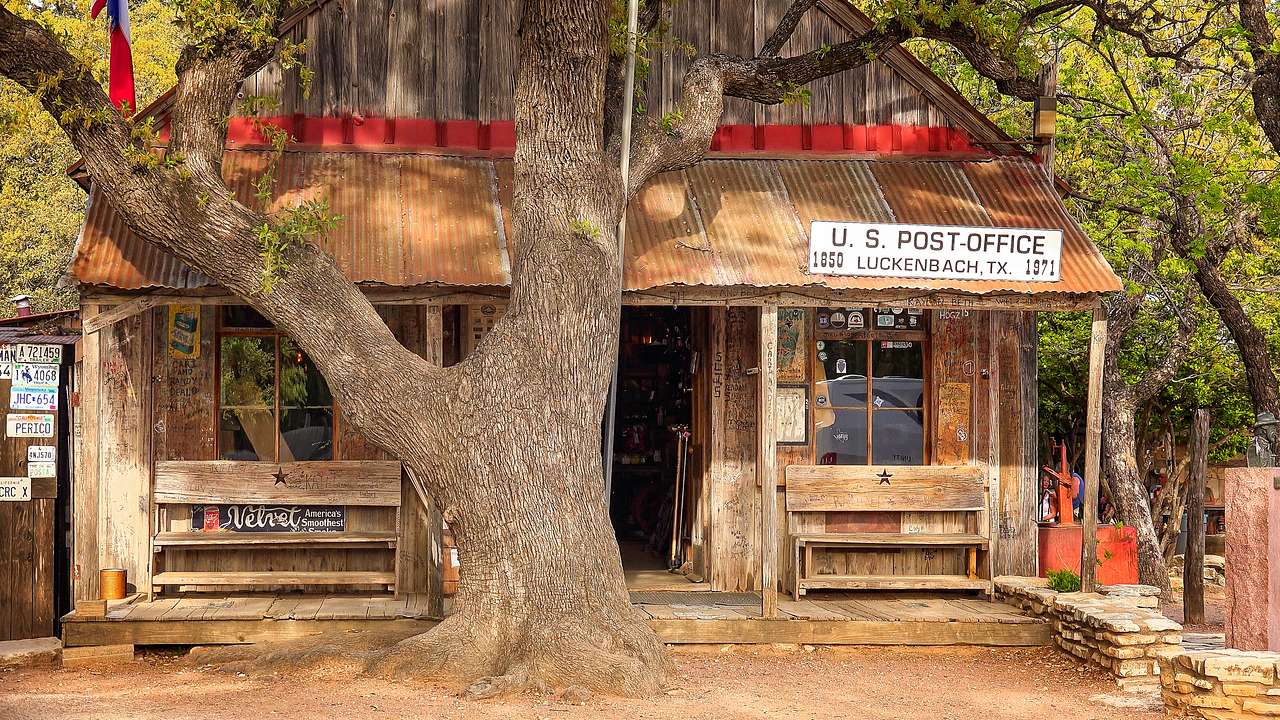 Wood structure with "US Post Office, Luckenbach Texas" signage, under a big tree