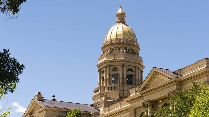 The top of a state capitol building with a tower with a gold dome atop it