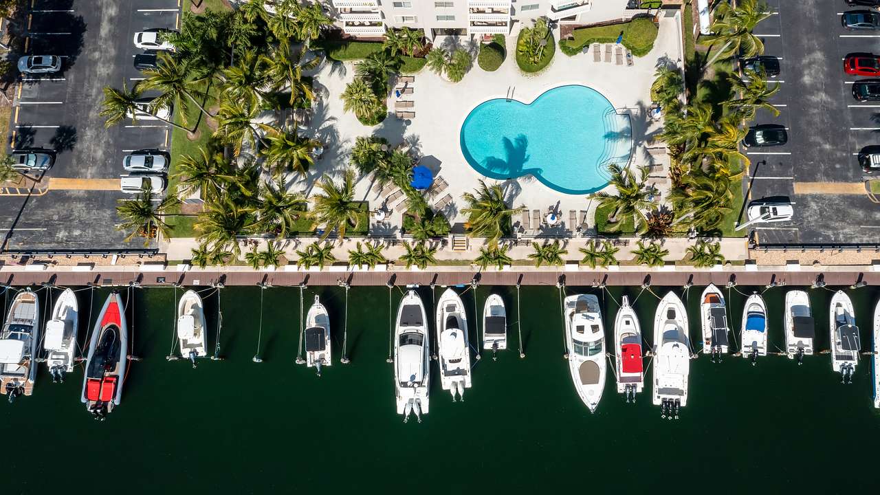 Aerial view of the water with boats and a pool alongside a white building