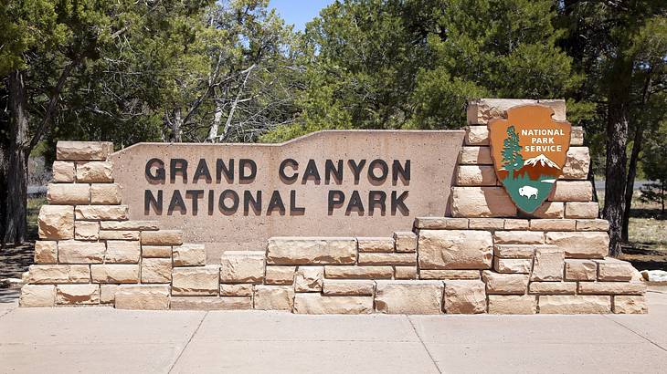 A sign on a white brick wall "Grand Canyon National Park" in black letters