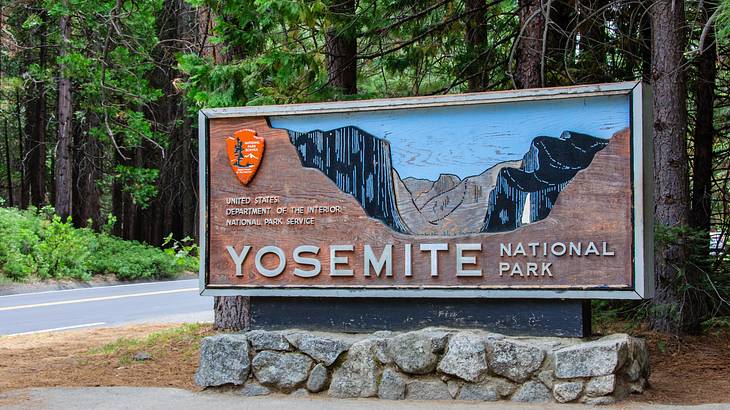 A brown sign on a grey brick wall "Yosemite National Park"