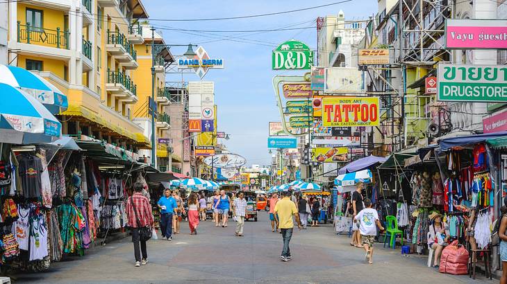 A street in Bangkok with colourful business signs and people walking around