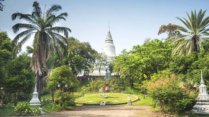 A temple with palm trees, grass, and a path in front of it