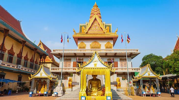 A temple with a yellow roof next to trees and a small square