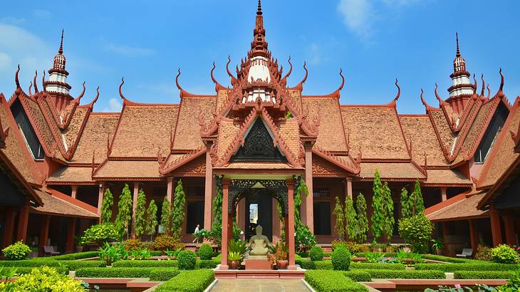 A unique Asian-style building next to a green garden on a clear day