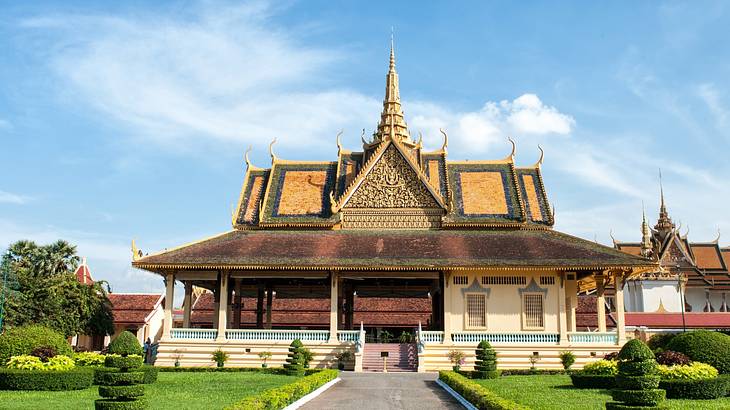 A small temple-like structure with green grass and bushes in front of it