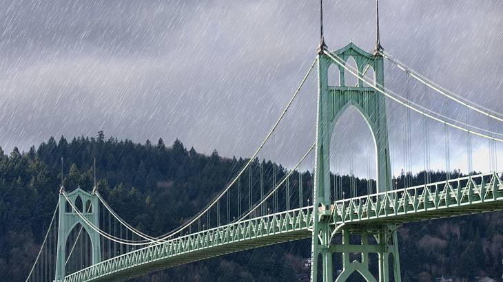 Rain over a green bridge and a river with trees in the background and a grey sky Rain over a green bridge and a river with trees in the background and a grey sky